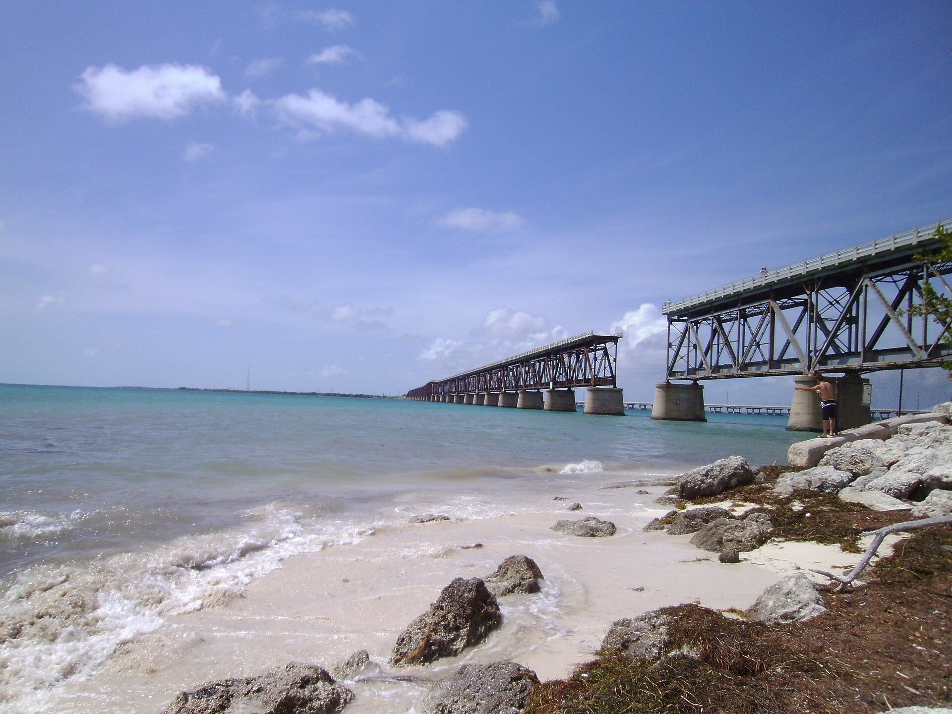 The abandoned Bahia Honda Rail Bridge seen from the sand at Calusa Beach with sargassum along the waterline