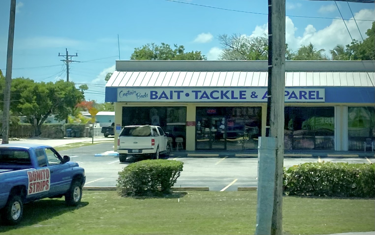 A bait, tackle and apparel shop beside the Overseas Highway in Key Largo with a pickup truck advertising bonito strips