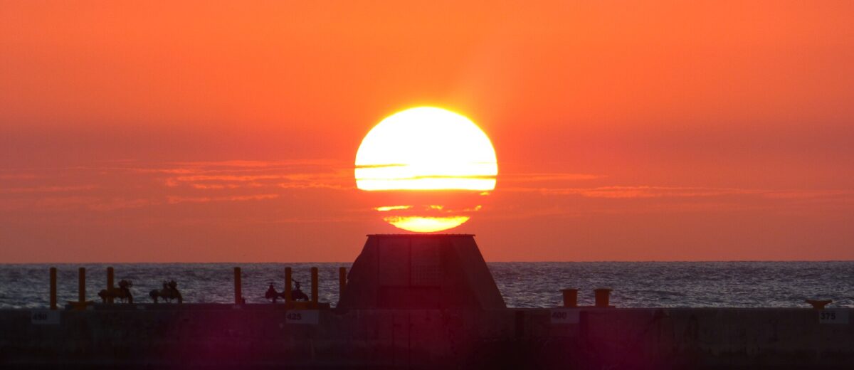 The sun setting in an orange sky over the pier at Truman Waterfront Park in Key West