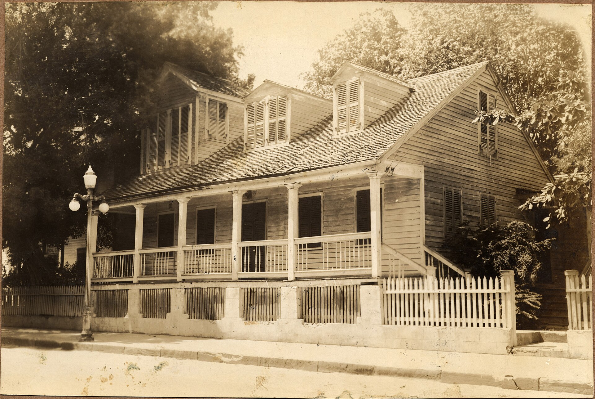 Historic 1934 photograph of the Captain Francis Watlington House, the Oldest House in Key West, with its long front porch, dormer windows and picket fence