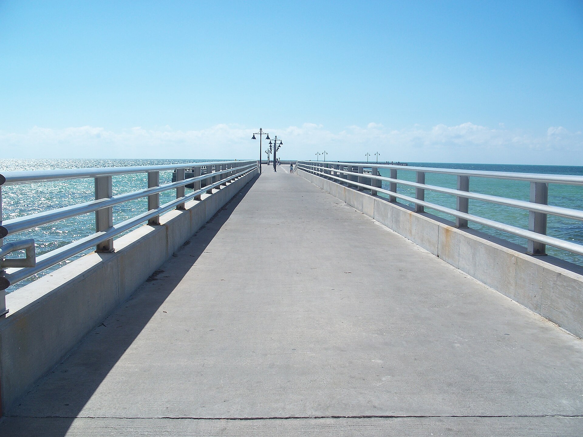 The long concrete White Street Pier stretching out into turquoise Atlantic water under a clear blue sky in Key West