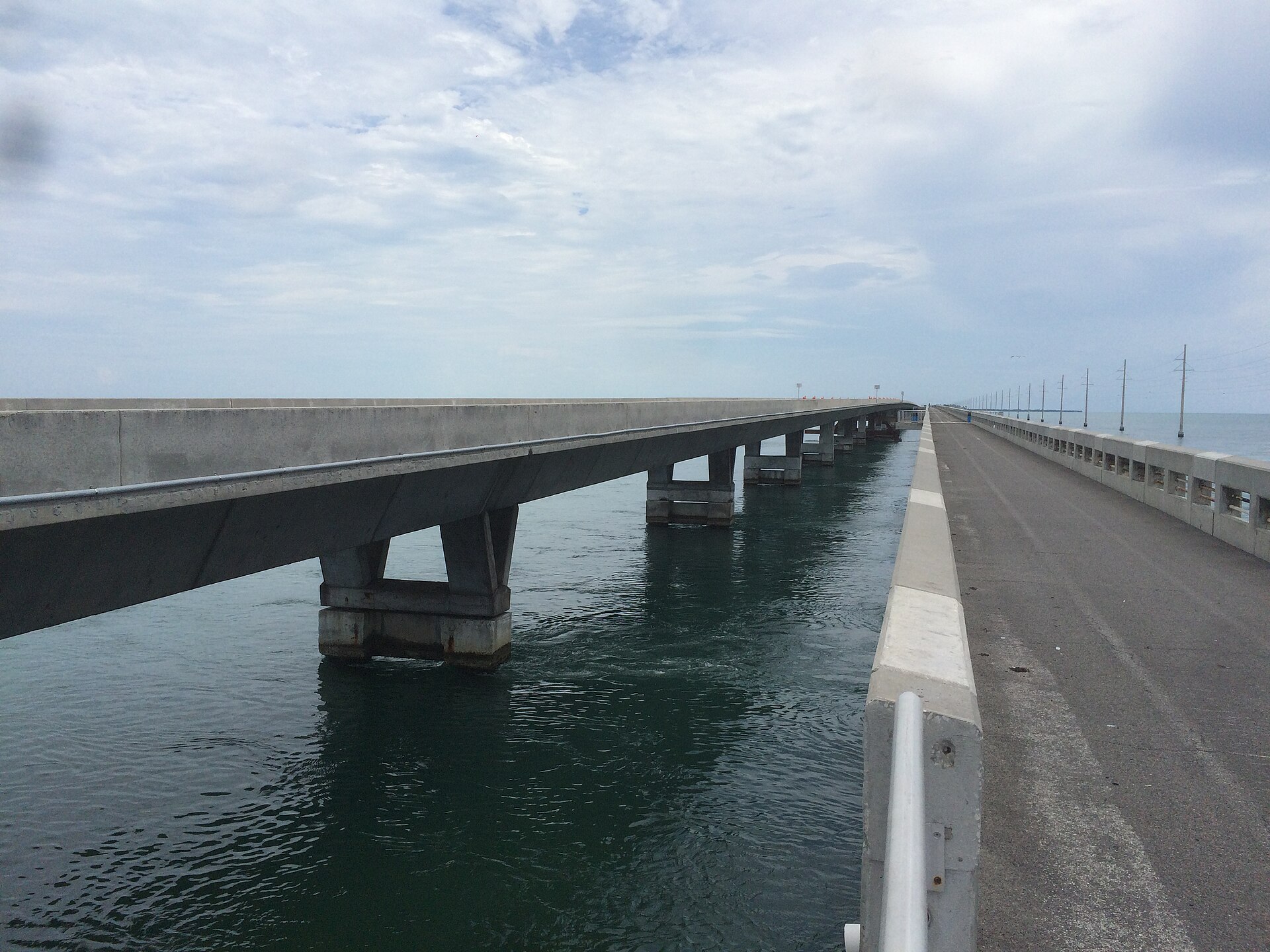 The old Long Key Bridge used as a walking and cycling path beside the modern concrete highway bridge over green water