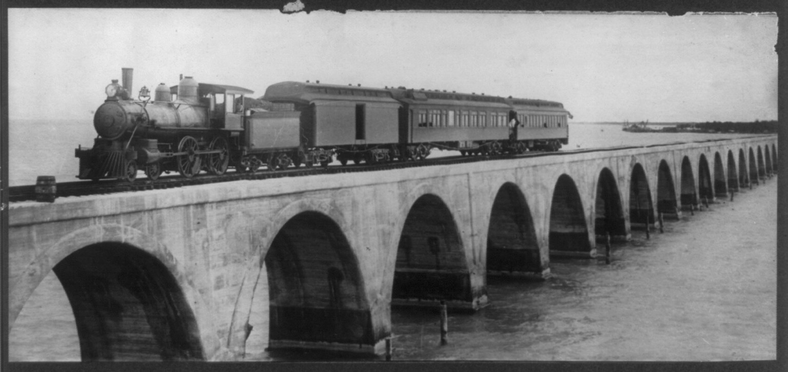 Black and white photograph of Henry Flagler's first train crossing the arched concrete Long Key Viaduct over open water