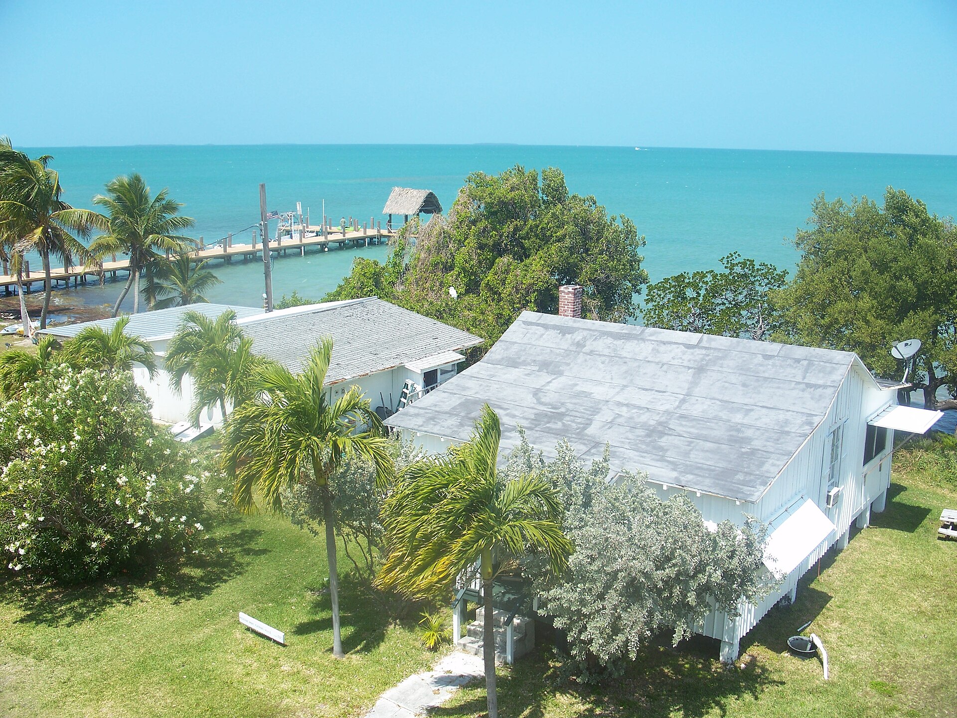 White clapboard railroad-era buildings and a dock on Pigeon Key seen from the old Seven Mile Bridge