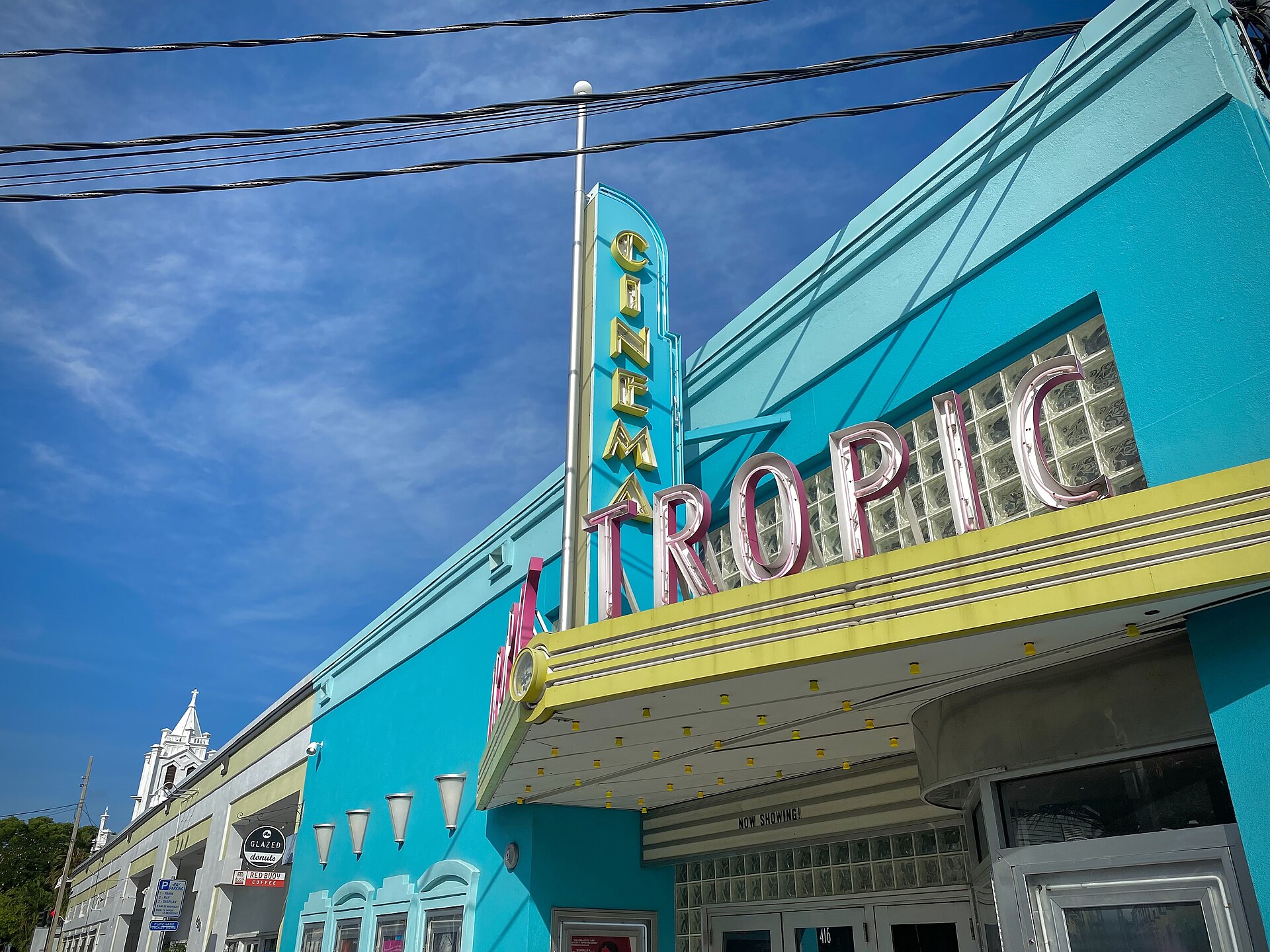 The turquoise art deco facade and neon Tropic Cinema sign on Eaton Street in Key West under a blue sky