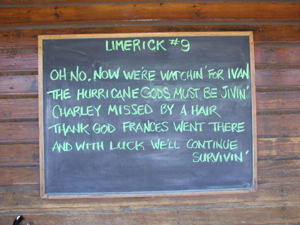 A chalkboard on a wooden wall with a handwritten limerick about hurricanes Ivan, Charley and Frances