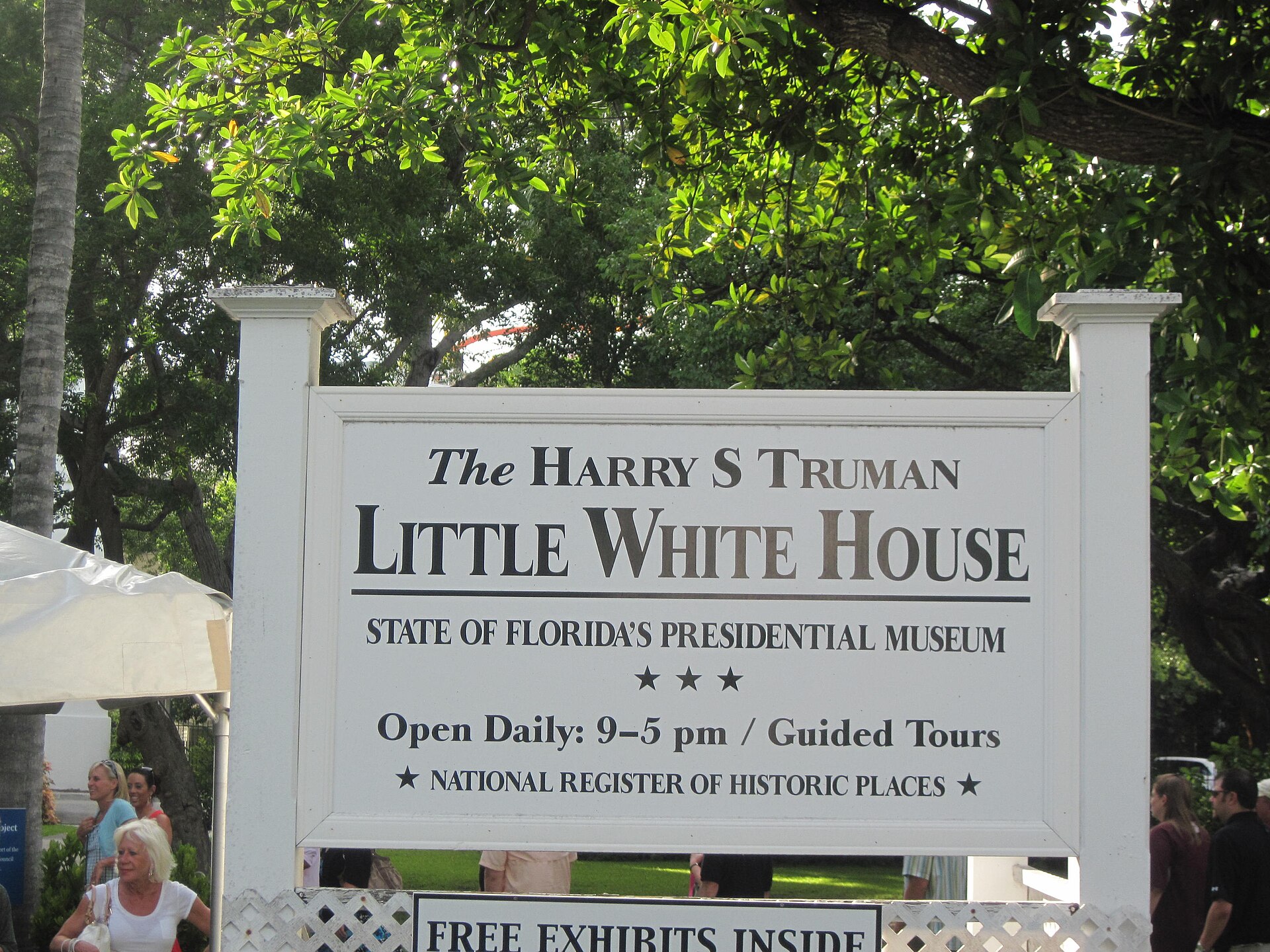 A white wooden sign reading The Harry S Truman Little White House, State of Florida's Presidential Museum, under trees